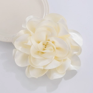 Detailed view of cream satin camellia flower brooch with layered petals and soft texture