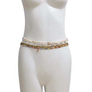 Detail van boheemse tailleketting met natuurlijke schelpen, goudkleurige zeester en kralen