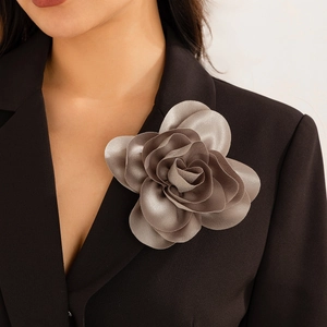 Nahaufnahme einer großen silbernen Stoffblumen-Brosche an einem schwarzen Blazer