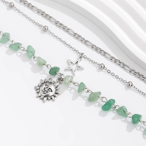 Detail eines mehrlagigen Boho-Armbands mit grünen Steinen und Stern-Sonne-Anhängern