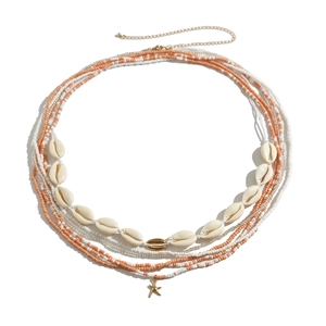 Detail van bohemien tailleketting met kralen, gouden zeester en natuurlijke schelpen