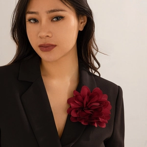 Detailansicht einer großen tiefroten Stoffblume als Brosche an einem schwarzen Blazer