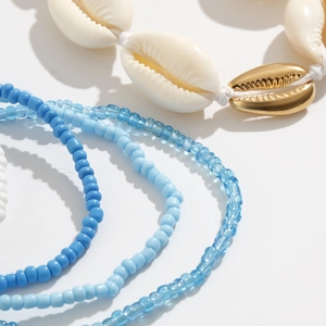 Detailweergave van boho buikketting met natuurlijke schelpen en blauwe glazen kralen