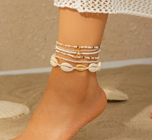 Detailopname van bohemian lichaamsketting met natuurlijke schelpen en zeester op strand
