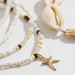 Detail van de bohemian strand lichaamsketting met gouden zeester, schelp en kralen