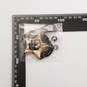 Detalle de colgante de estrella de mar dorada con logo G calado en cordón negro sellado