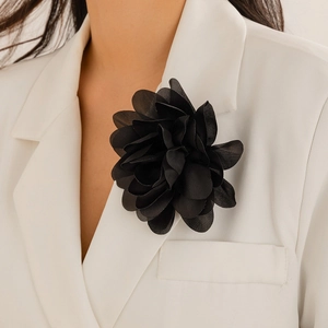 Detail einer eleganten schwarzen Stoffblumen-Brosche an einem weißen Revers
