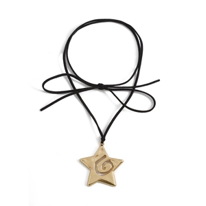 Detalle macro del colgante de estrella dorada con grabado espiral y cordón negro fino