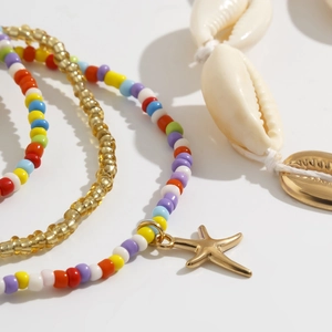 Detailopname van bohemian strandlichaamsketting met gekleurde kralen en gouden zeester