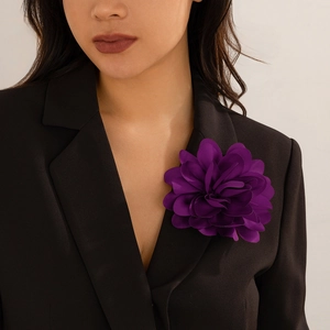 Detail einer großen dunkelvioletten Stoffblume Brosche an einem schwarzen Blazer