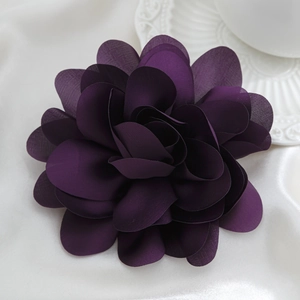 Makroaufnahme einer dunkelvioletten Stoffblume Brosche mit feinen Seidenblütenblättern