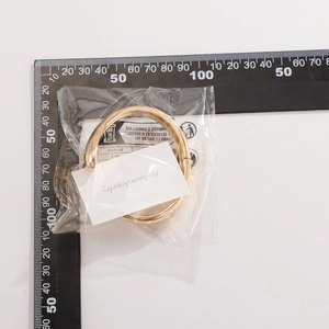 Makroansicht des goldenen Wassertropfen-Armreifs mit Federgelenk in QC-Verpackung