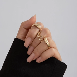 Detailed view of irregular wavy gold-tone ring set with unique embossed texture