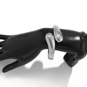 Makro-Detail des klobigen silbernen Tropfen-Armreifs mit polierter Oberfläche auf Hand