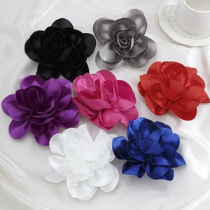 Mehrfarbige Stoffrosen-Anstecknadeln aus Satin auf elegantem weißem Seidenhintergrund