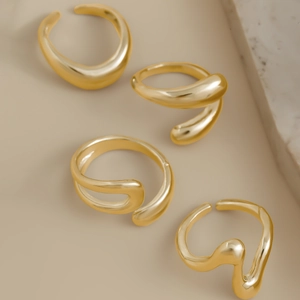 Macro detail of four gold irregular organic lava rings with polished metallic finish