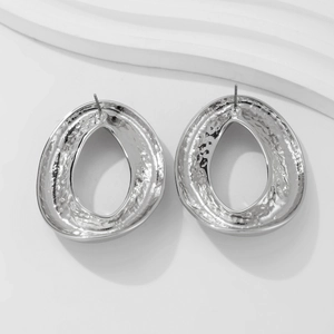 Vista dettagliata di orecchini a perno ovali in argento con texture martellata e design moderno