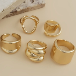 Close-up of five-piece gold irregular ring set with molten lava design and chunky metal finish