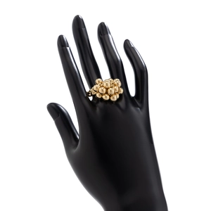 Detailansicht eines markanten goldenen Perlenrings an der Hand vor weißem Hintergrund