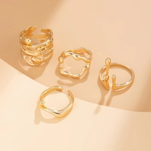 Detailed view of four irregular liquid lava style gold rings on beige display stands