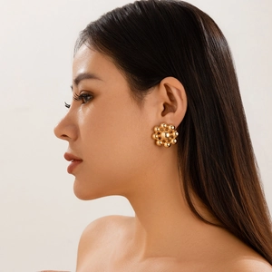 Close-up of geometric golden cluster bead earrings worn on a model for a chic look