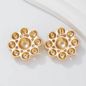 Detailed back view of gold flower earrings with petal design on white minimalist props