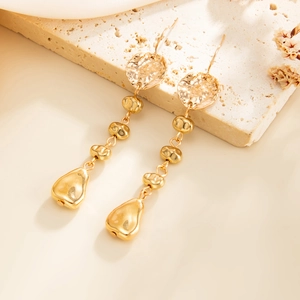 Détail de boucles d'oreilles dorées avec disques métalliques et franges de perles d'eau