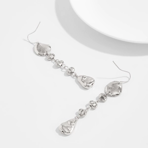 Vue macro des boucles d'oreilles argentées avec pendentifs en métal liquide texturé