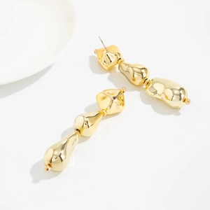 Détail de boucles d'oreilles dorées à pampilles avec texture métallique irrégulière
