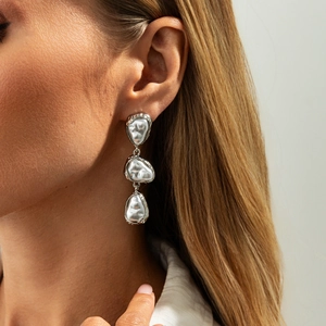 Gros plan de boucles d'oreilles pendantes argentées à trois couches sur un mannequin chic