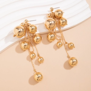 Gros plan détaillé de boucles d'oreilles à pompons en perles dorées au fini miroir poli