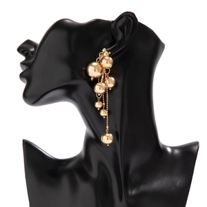 Détail de boucles d'oreilles dorées à pampilles perlées avec chaînes sur un mannequin