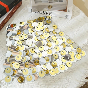 Dettaglio di minigonna in paillettes metalliche argento e oro con texture da festa