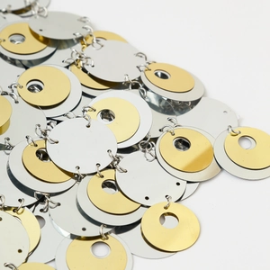 Dettaglio di paillettes metalliche oro e argento sovrapposte collegate da anelli di corpo