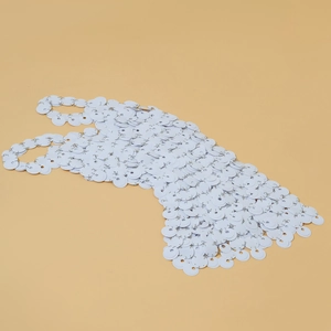 Dettaglio macro del top in maglia a dischi bianchi con anelli di collegamento in metallo