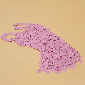 Dettaglio macro del top bikini con paillettes rosa e anelli metallici collegati
