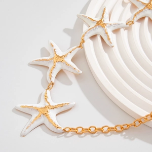 Macro shot of white starfish charm with gold edges on a chic body chain accessory