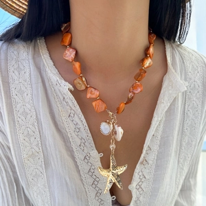 Dettaglio della collana boho con perle di conchiglia arancioni e ciondolo a stella