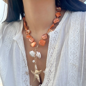 Dettaglio della collana in stile marino con perline arancioni e ciondolo a stella marina