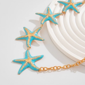 Macro shot of gold-plated starfish body chain with turquoise enamel details and texture