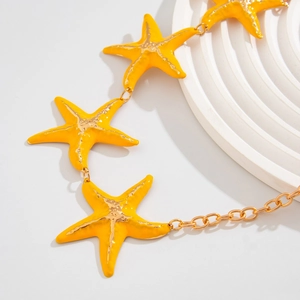 Detailed close-up of yellow enamel starfish charms on a gold body chain with metal links