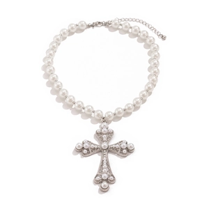 Detailed macro view of punk cross pendant with micro-set pearls on layered necklace