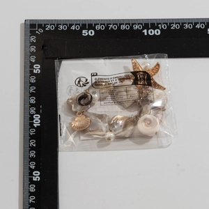 Marine style necklace with shell pieces, pearls and starfish charms next to a ruler