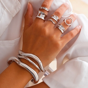 Dettaglio del set di anelli lava irregolari e bracciali rigidi ondulati lucidi da donna