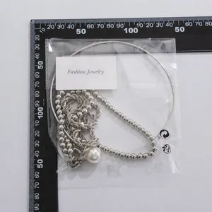 Detail of punk metal collar and faux pearl necklace set measured on a black scale