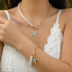 Dettaglio della collana e bracciale con stella marina, perle e chiusura a levetta
