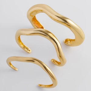 Vista dettagliata di tre bracciali aperti dorati stile lava irregolare in set