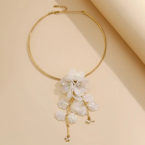 Détail macro du pendentif fleur en nacre irisée sur un collier ras du cou doré