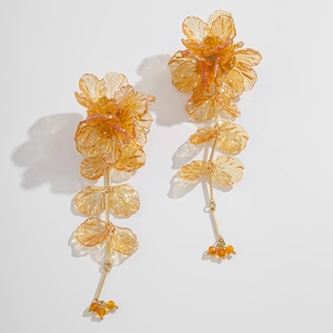 Détail des boucles d'oreilles fleurs en résine ambre avec chaînes dorées et feuilles
