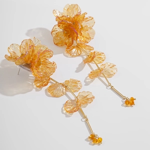 Détail de longues boucles d'oreilles fleuries ambrées avec des pétales en résine